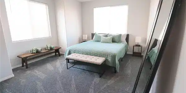 Image 4: Well-lit master bedroom with plush carpeting and a