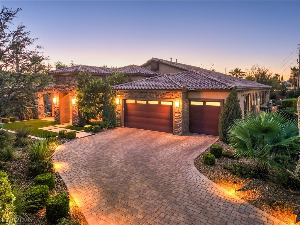 Image 1: Illuminated paver driveway and lush landscaping de