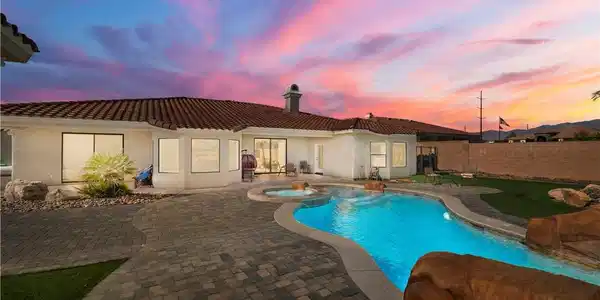 Image 4: A custom pool and spa beckon under a vivid sunset,