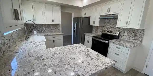 Image 3: This modern kitchen features gleaming granite coun