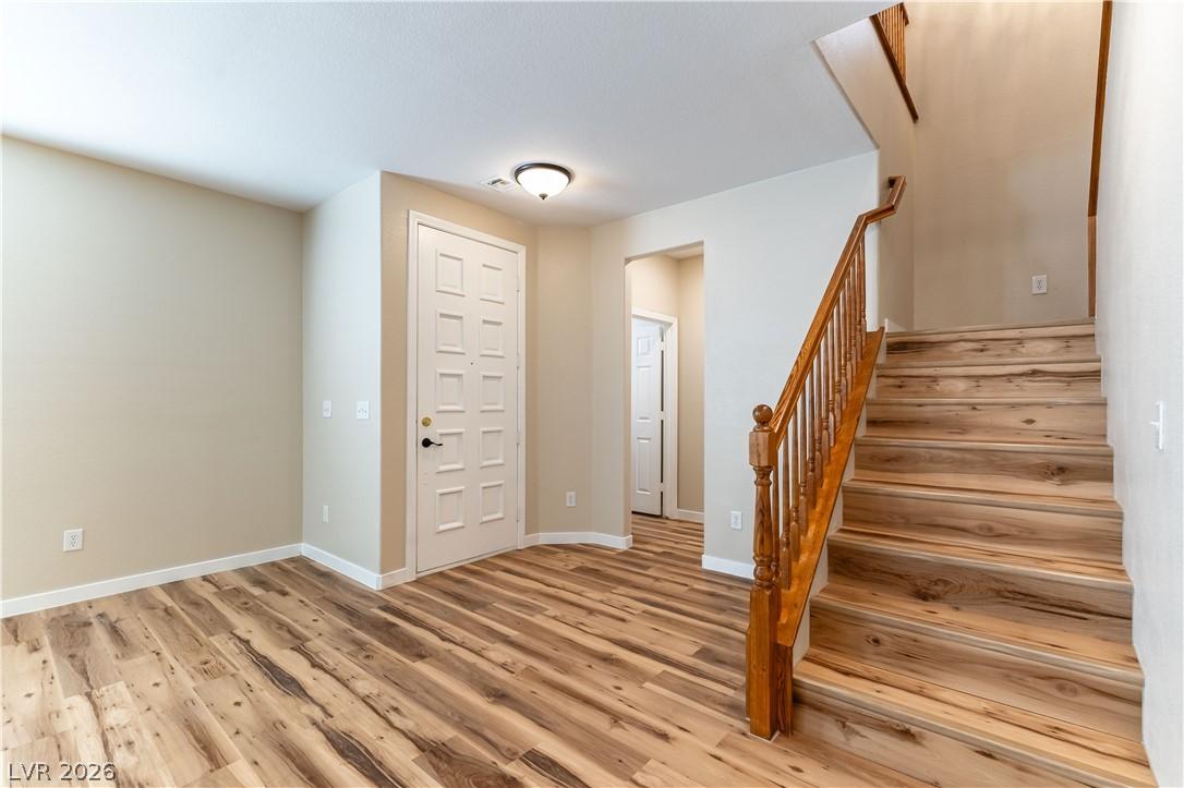 Image 4: A welcoming entryway with rich wood flooring leads