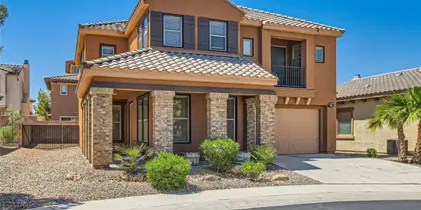 Image 3: Earth-toned stucco siding and textured stone pilla