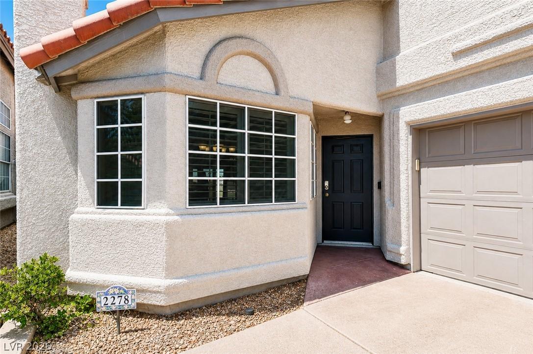 Image 2: A welcoming stucco facade features a dark entry do