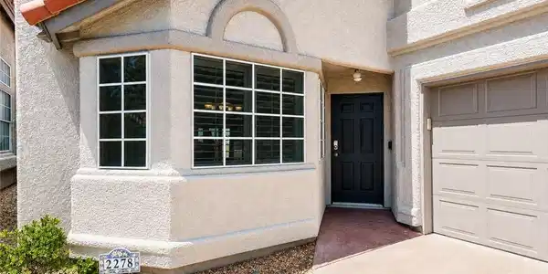 Image 2: A welcoming stucco facade features a dark entry do