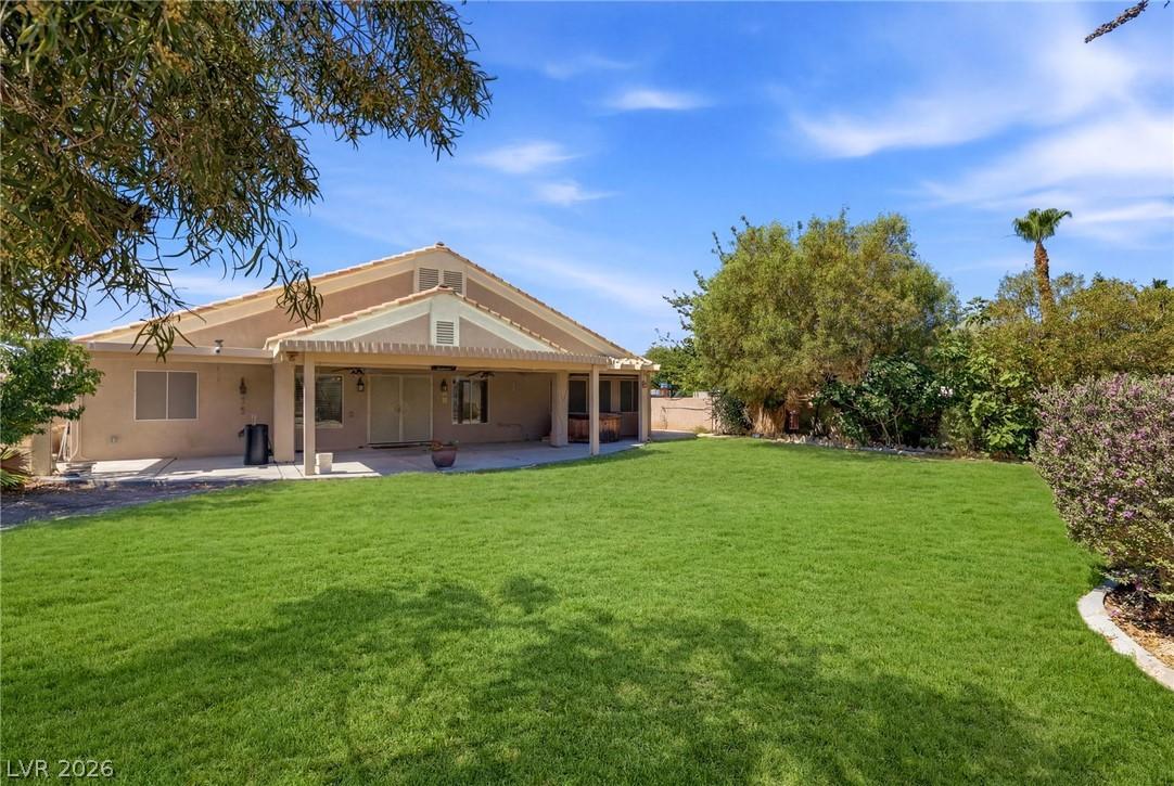 Image 2: A generous verdant lawn extends from a covered pat