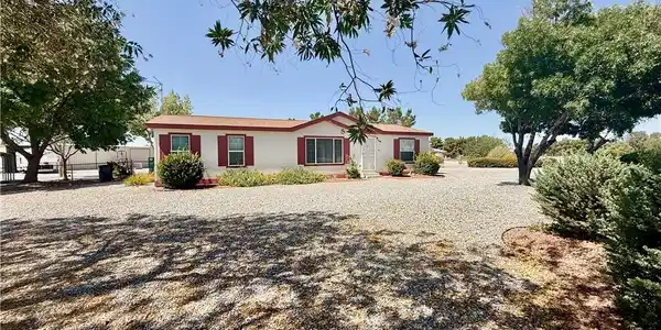 Image 2: A quaint residence sits amid a large gravel yard a