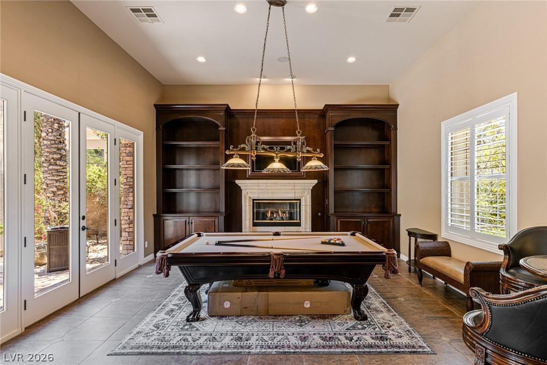 Image 3: An inviting game room features an elegant fireplac