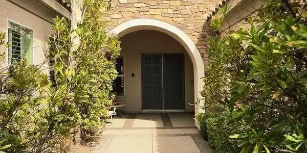 Image 3: A paved walkway leads past lush plantings to a sto