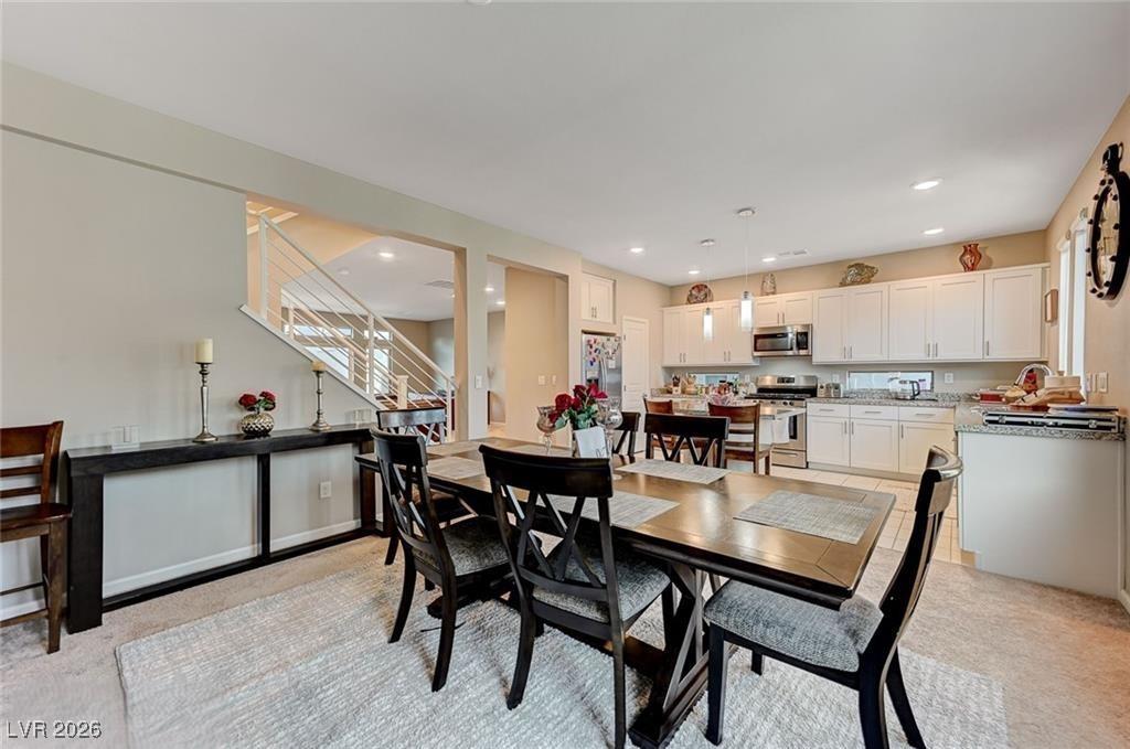 Image 1: Dining space featuring light colored carpet, stair