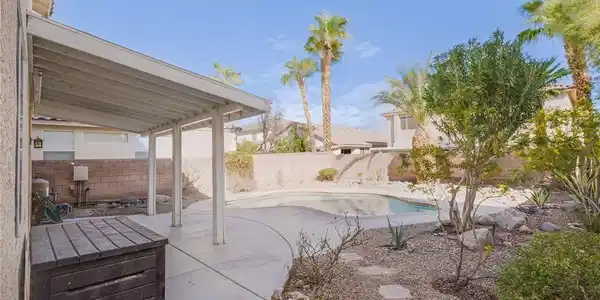 Image 4: An inviting backyard pool is flanked by a covered