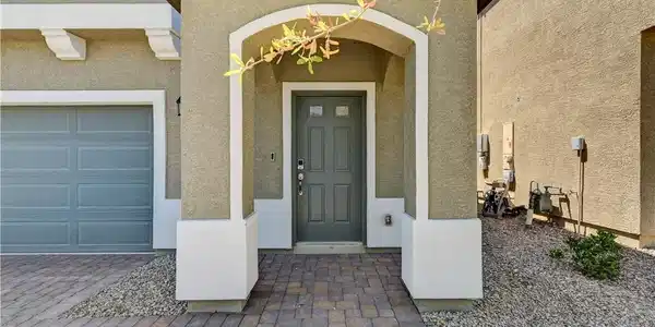 Image 2: An arched covered entry and paved walkway create a