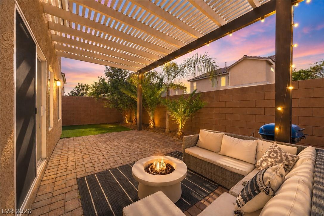 Image 4: An inviting backyard patio features a pergola, pav