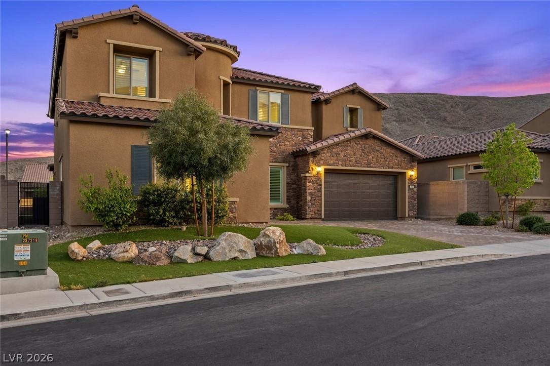 Image 1: A striking stucco and stone residence, featuring a