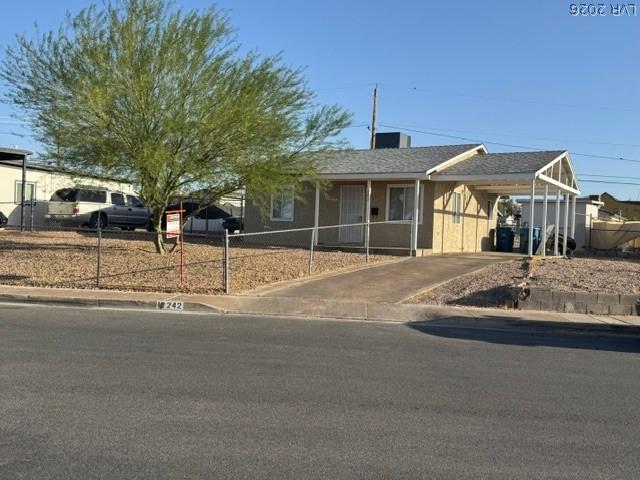 Image 1: A modest desert home with a paved driveway and gra