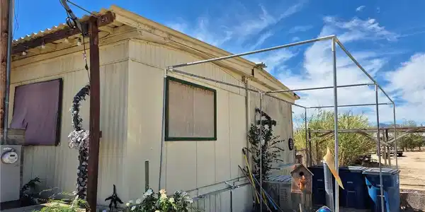 Image 2: Metal siding and a covered patio frame this modest