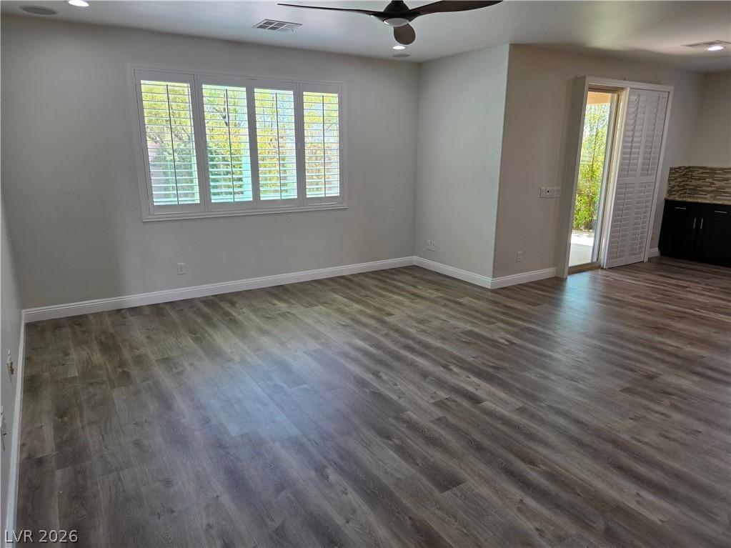 Image 2: A spacious room features rich wood flooring, crisp