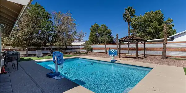 Image 4: An inviting backyard oasis features a sparkling sw