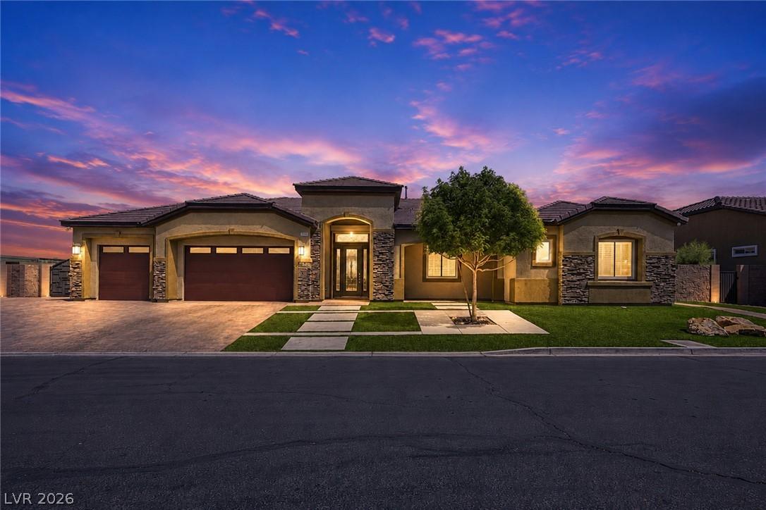 Image 1: A spacious home with stone accents and a paver dri