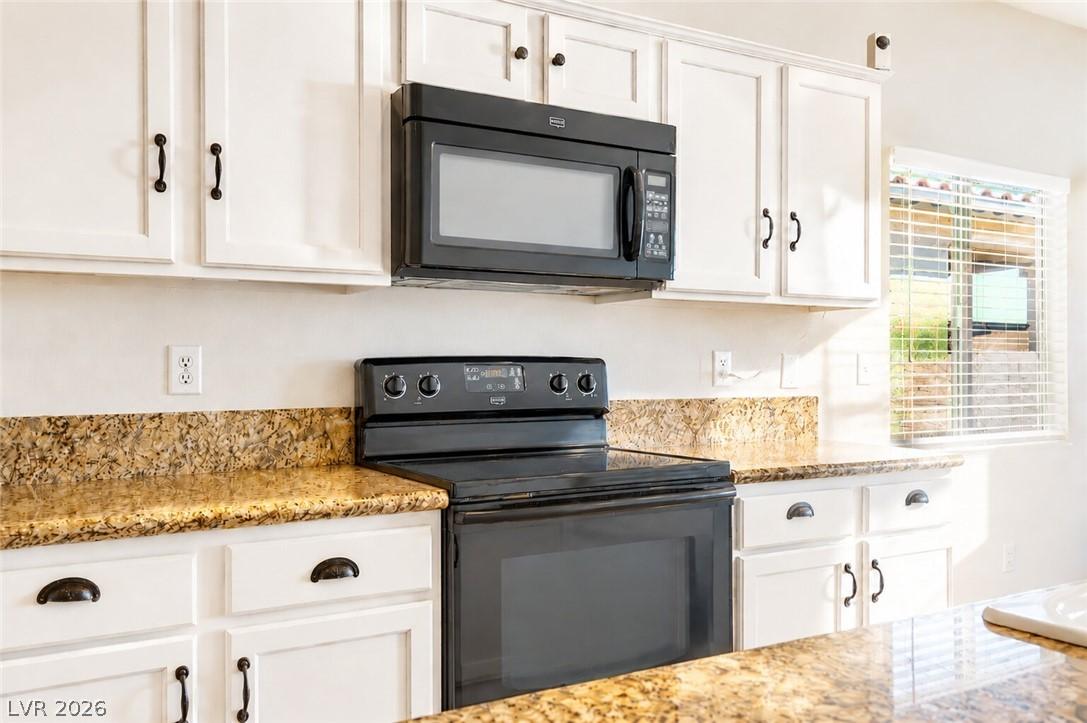 Image 3: A well-appointed kitchen features ample white cabi