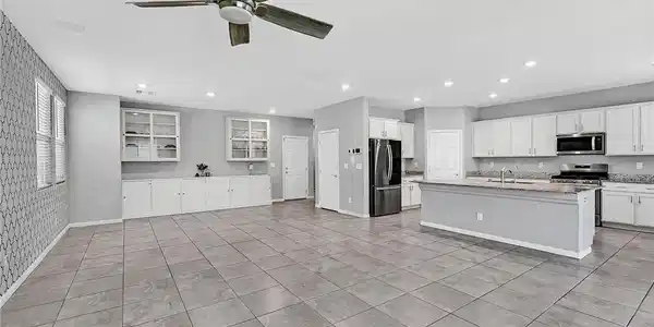 Image 3: An open-concept living area boasts a modern kitche