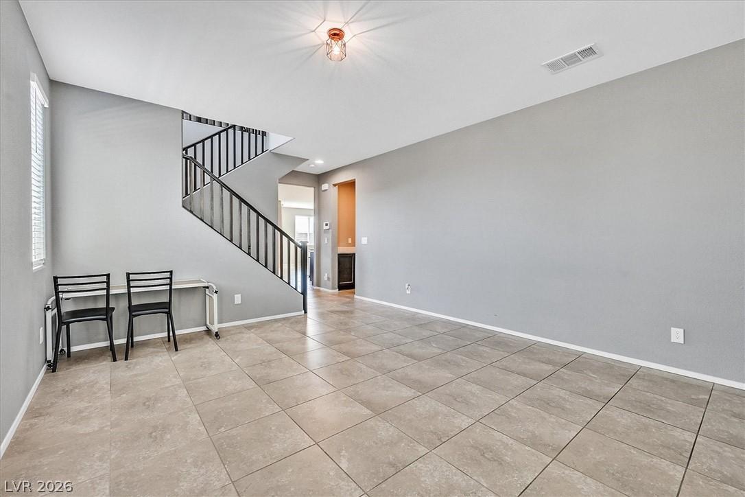 Image 4: A spacious living area with tile flooring and a sl