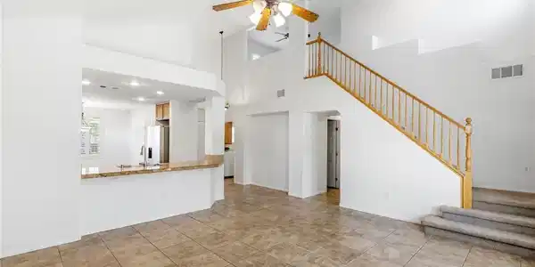 Image 2: A grand staircase ascends beside an open-concept l