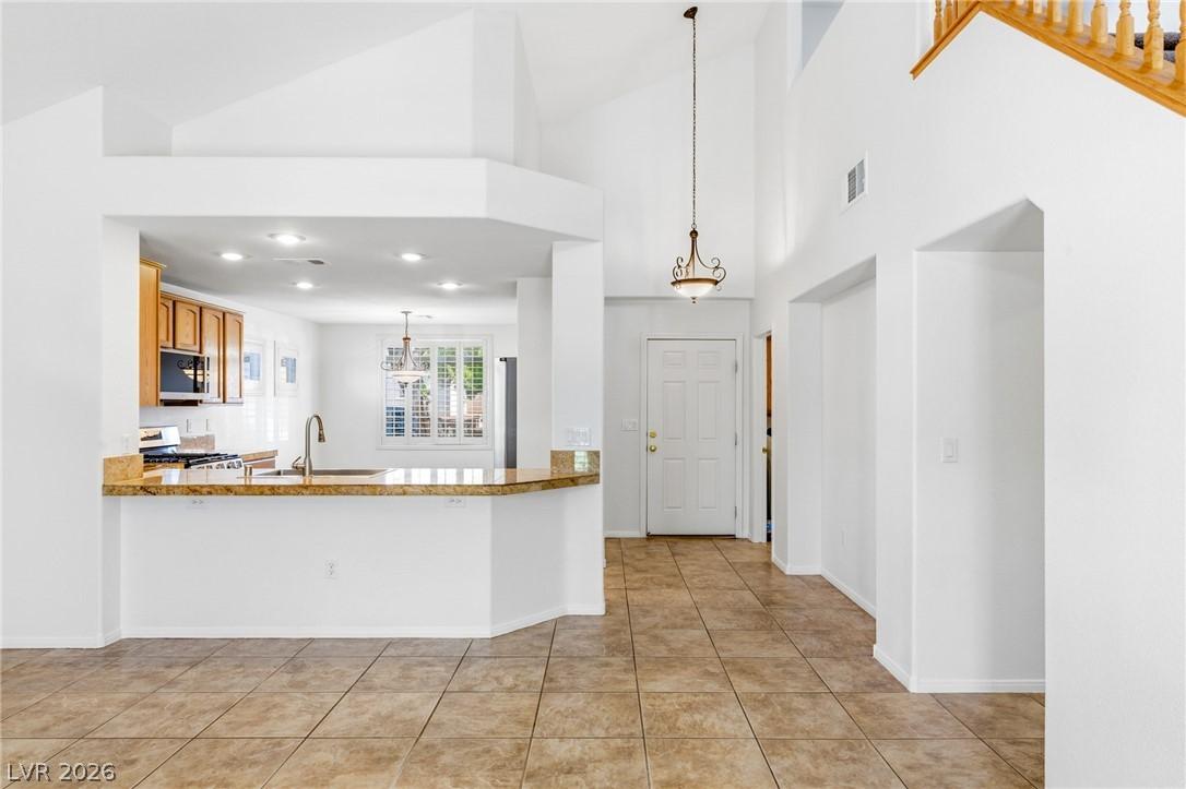 Image 4: A spacious entry and kitchen area with vaulted cei