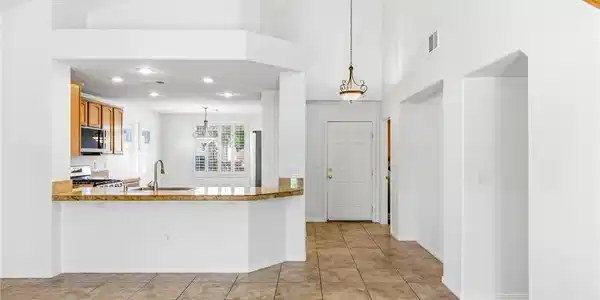 Image 4: A spacious entry and kitchen area with vaulted cei