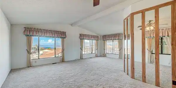 Image 3: Vaulted ceilings and broad windows frame distant h