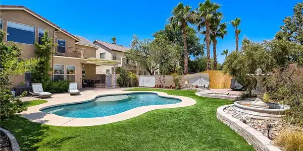 Image 2: A tranquil backyard oasis features a freeform pool