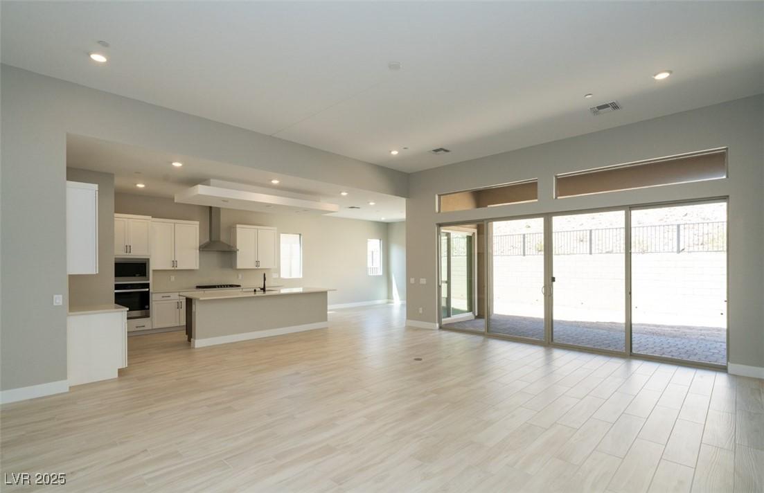 Image 2: Unfurnished living room with light wood-style floo