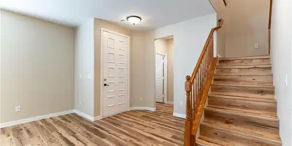 Image 4: A welcoming entryway with rich wood flooring leads