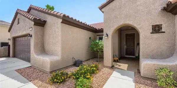 Image 4: An arched covered entry and low-maintenance landsc