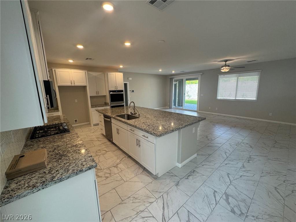 Image 3: An open concept kitchen features abundant granite