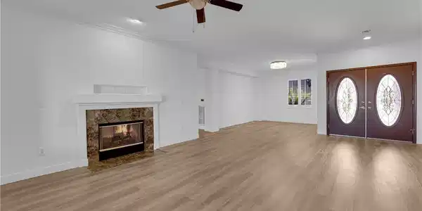 Image 4: Warm wood-look flooring and a classic fireplace an