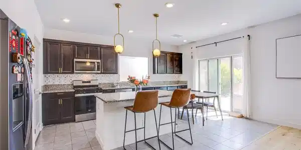 Image 3: Kitchen featuring dark wood finish cabinets, stain
