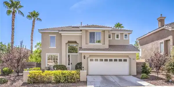 Image 2: Sunlight bathes a classic two-story stucco exterio