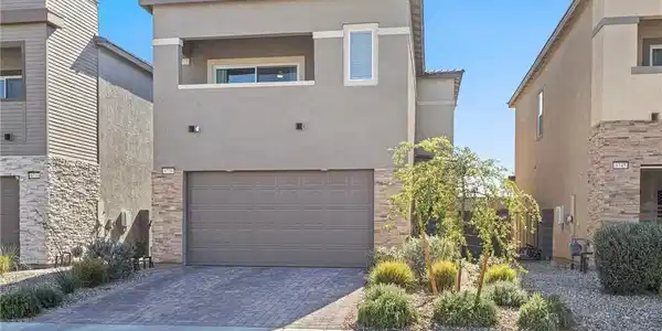 Image 2: A modern facade with a paver driveway, accented by