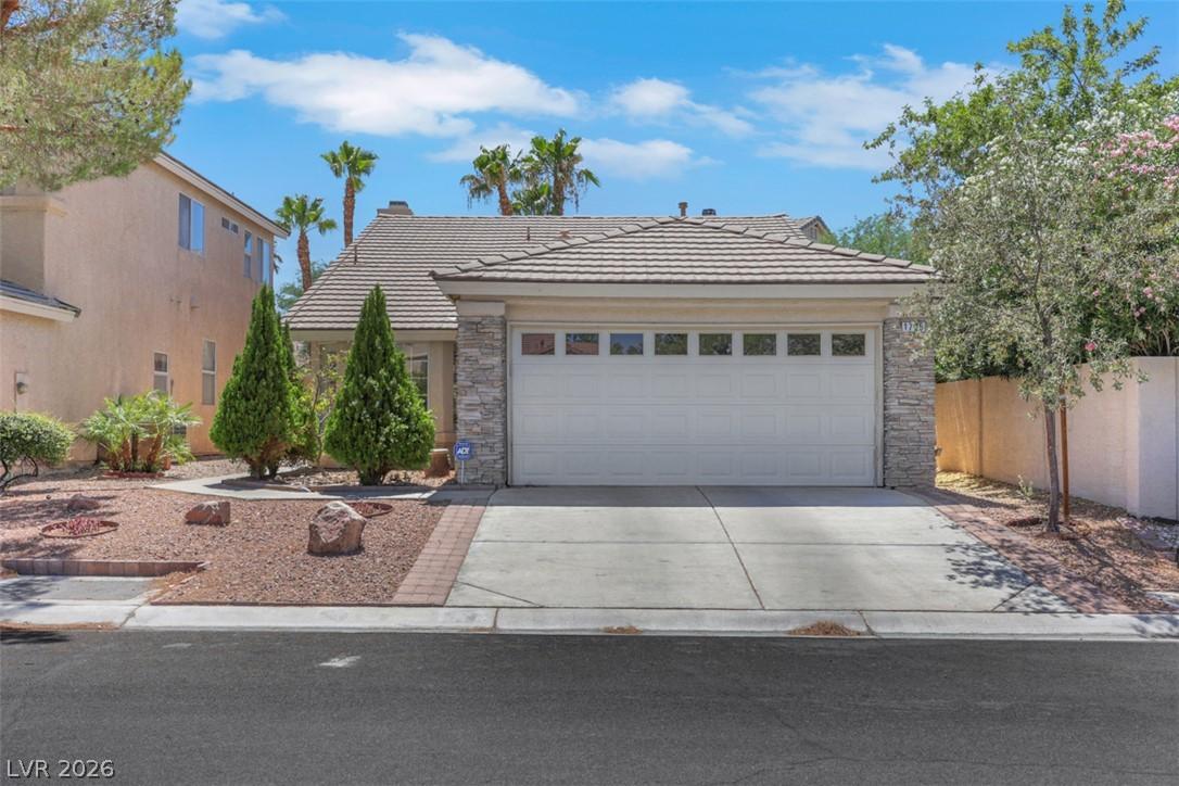 Image 4: Stone facade, desert landscaping, and a two-car ga