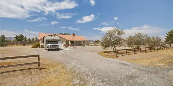 Image 3: An expansive gravel driveway leads past wooden fen