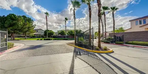 Image 2: Stately wrought iron gates frame the paved entrywa