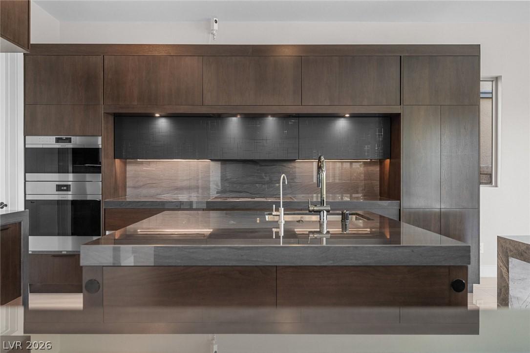 Image 4: A sleek modern kitchen with dark wood cabinetry an
