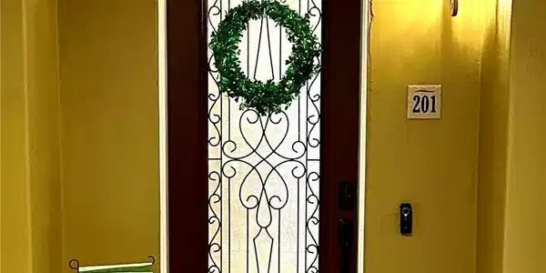 Image 3: A dark-stained entry door features an ornate wroug