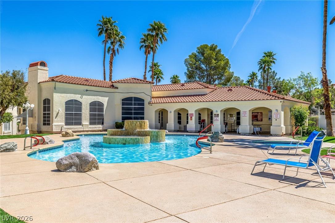 Image 2: Rear view of house with a community pool, stucco s