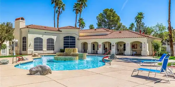 Image 2: Rear view of house with a community pool, stucco s