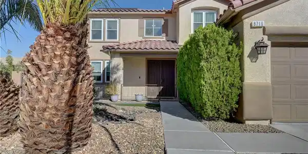 Image 4: A concrete walkway leads past desert landscaping t