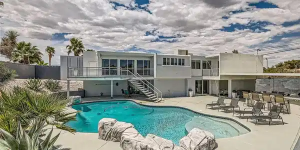 Image 2: View of pool featuring stairs, a patio, and a bar