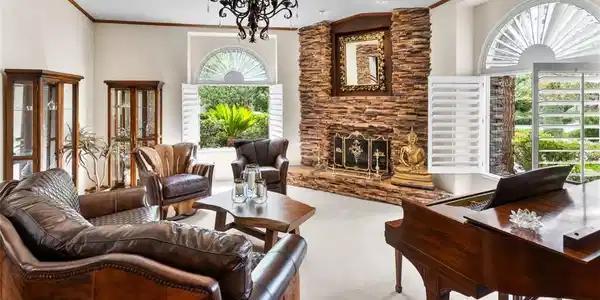 Image 2: Grand living room features a stone fireplace, arch