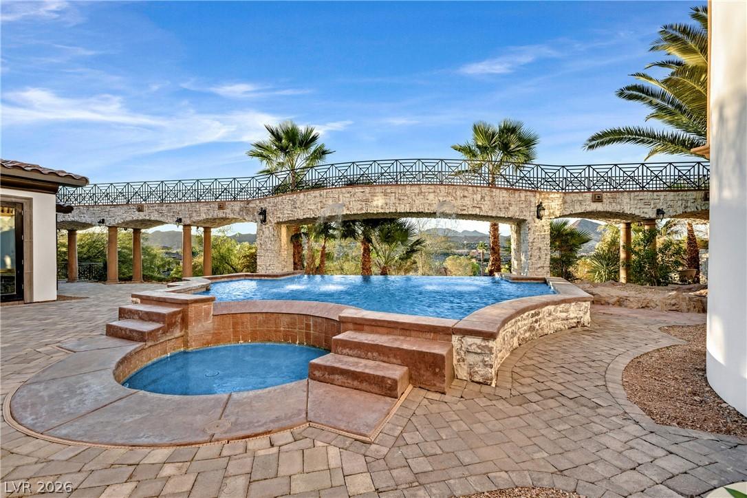Image 3: An inviting pool and spa beckon with a stone bridg