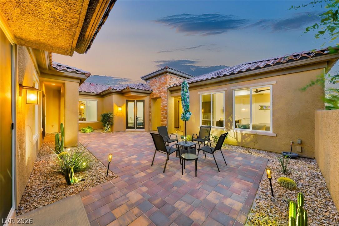 Image 4: An inviting paver patio extends from a stucco home